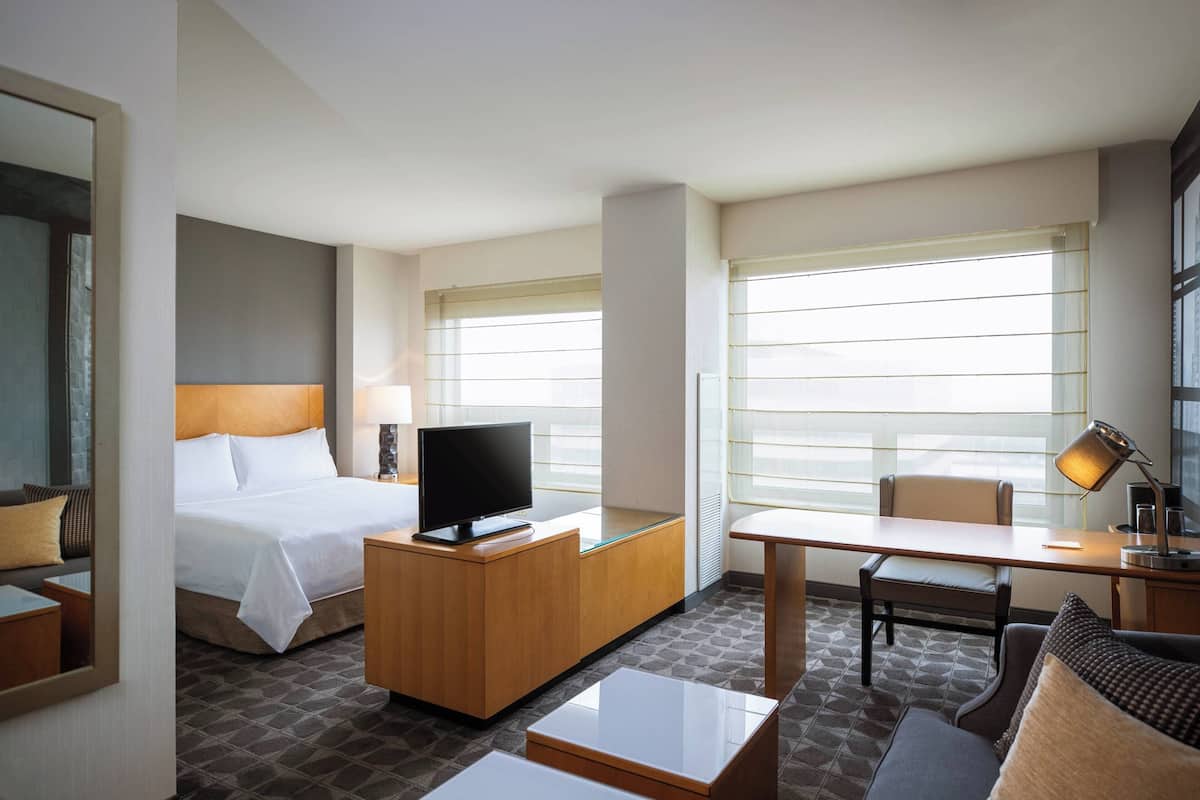 A hotel room with a bed, desk, chair, and a television.