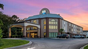 A hotel with a modern design, featuring a large entrance with a covered walkway, multiple windows, and a parking area with cars. - Best Western Carowinds (Fort Mill)