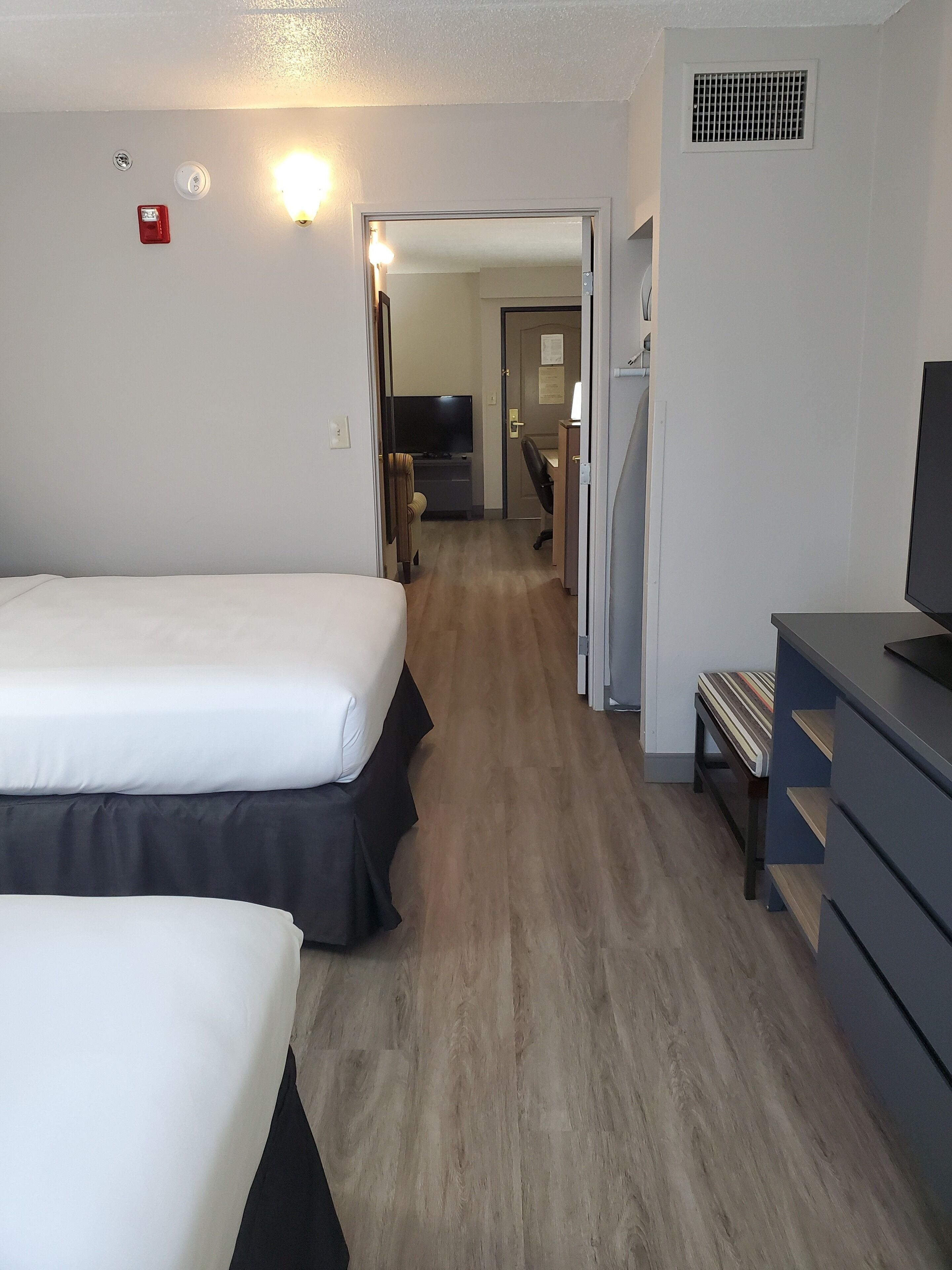 Une chambre d’hôtel avec deux lits, un bureau, une télévision et une armoire.