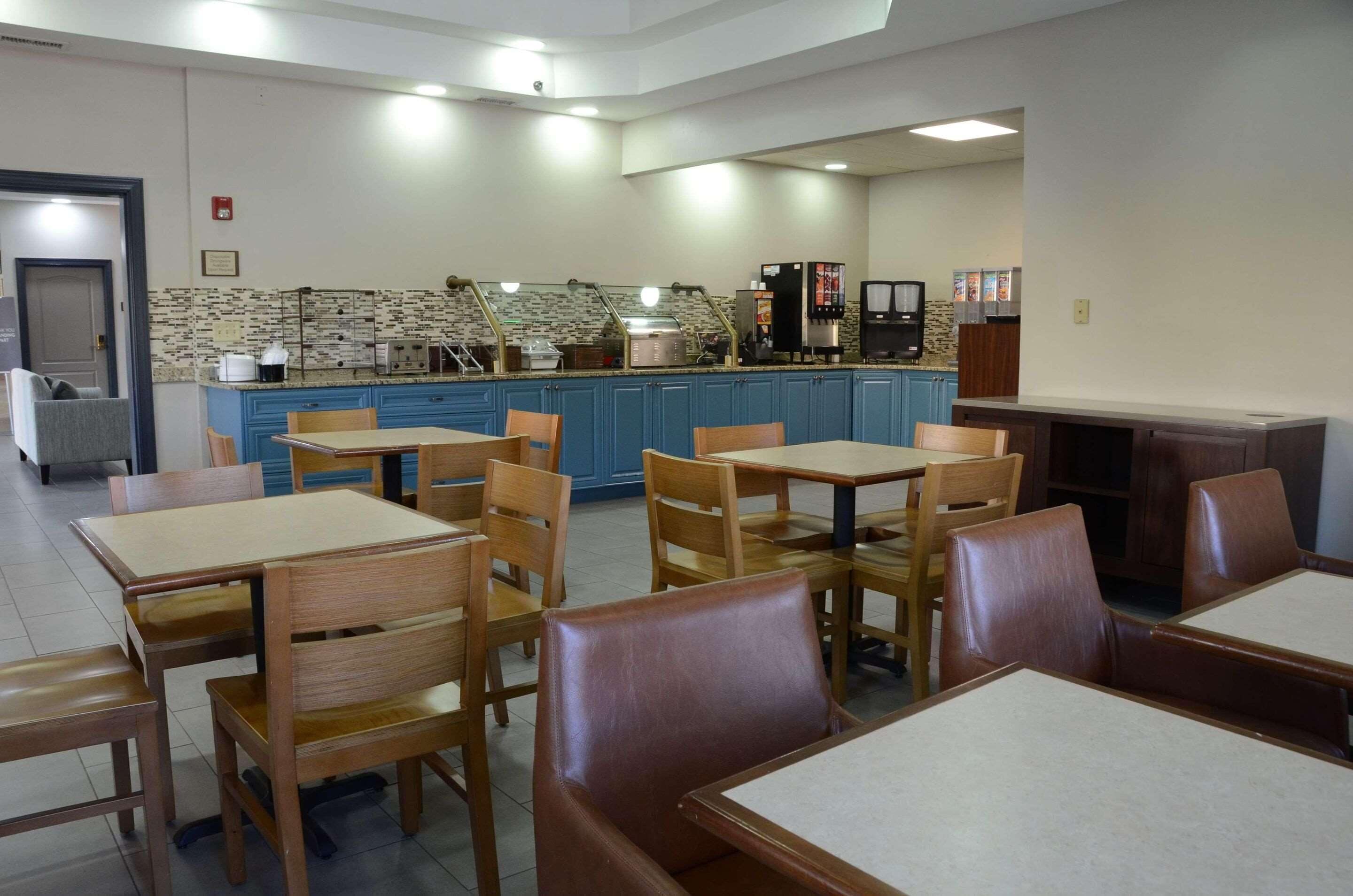 A dining area with tables and chairs, a kitchen area with appliances, and a counter with a coffee machine.