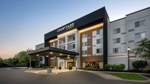 A Courtyard by Marriott hotel with a modern design, featuring a covered entrance and a landscaped courtyard. - Courtyard by Marriott Edison Woodbridge (Edison)