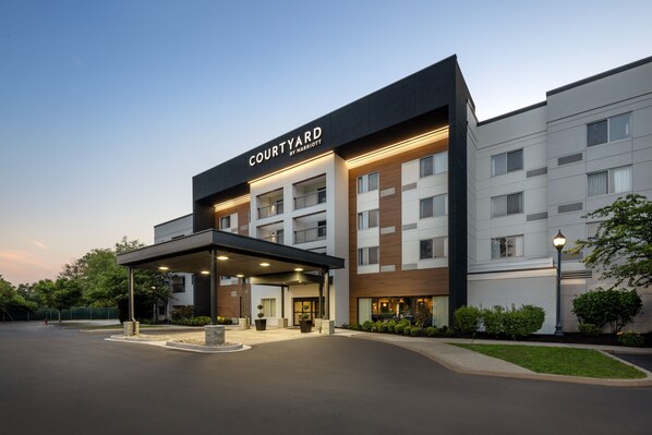 Welcome to Courtyard Marriott, featuring a modern entrance with a flat roof canopy and lush greenery.