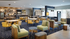A modern hotel lobby with multiple seating areas, a bar, and a dining area. - Courtyard by Marriott Edison Woodbridge (Edison)