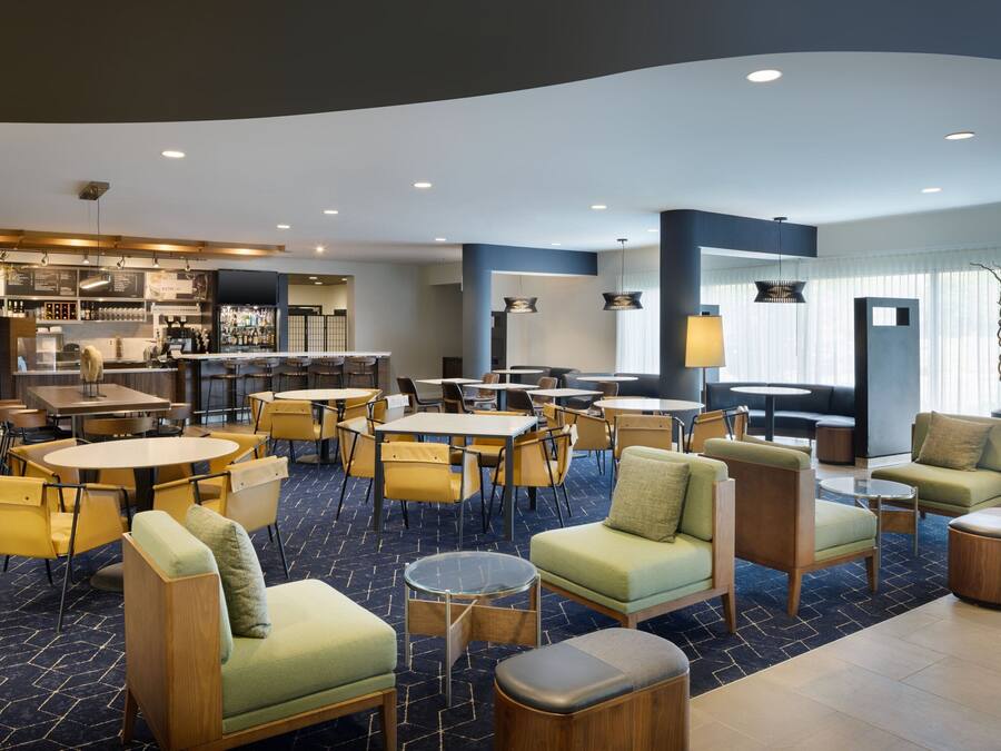 A modern hotel lobby with multiple seating areas, a bar, and a dining area.