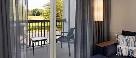 A room with a balcony, a sofa, and a table.