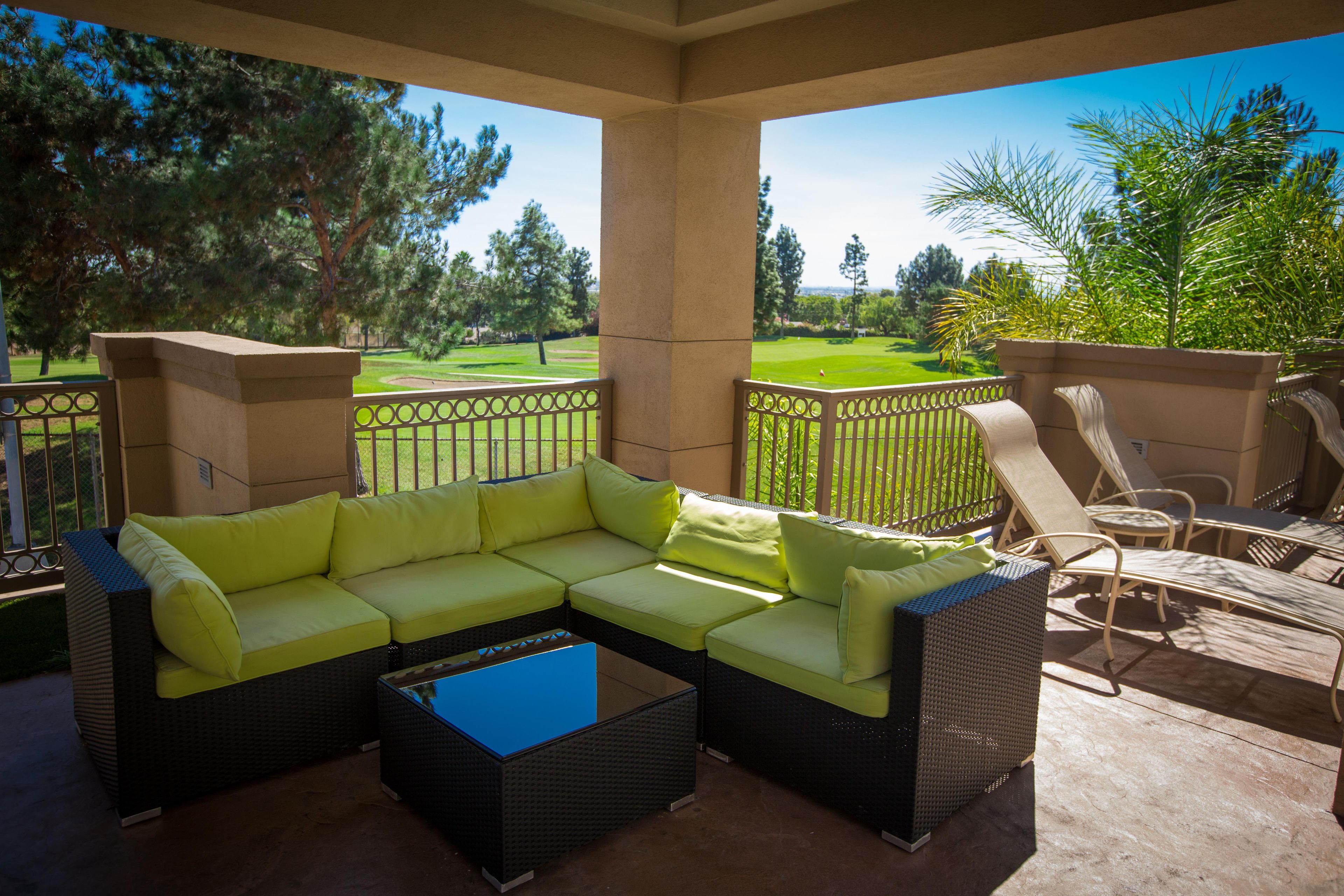 Un área de estar al aire libre cubierta con un sofá modular, una mesa de centro y sillones.