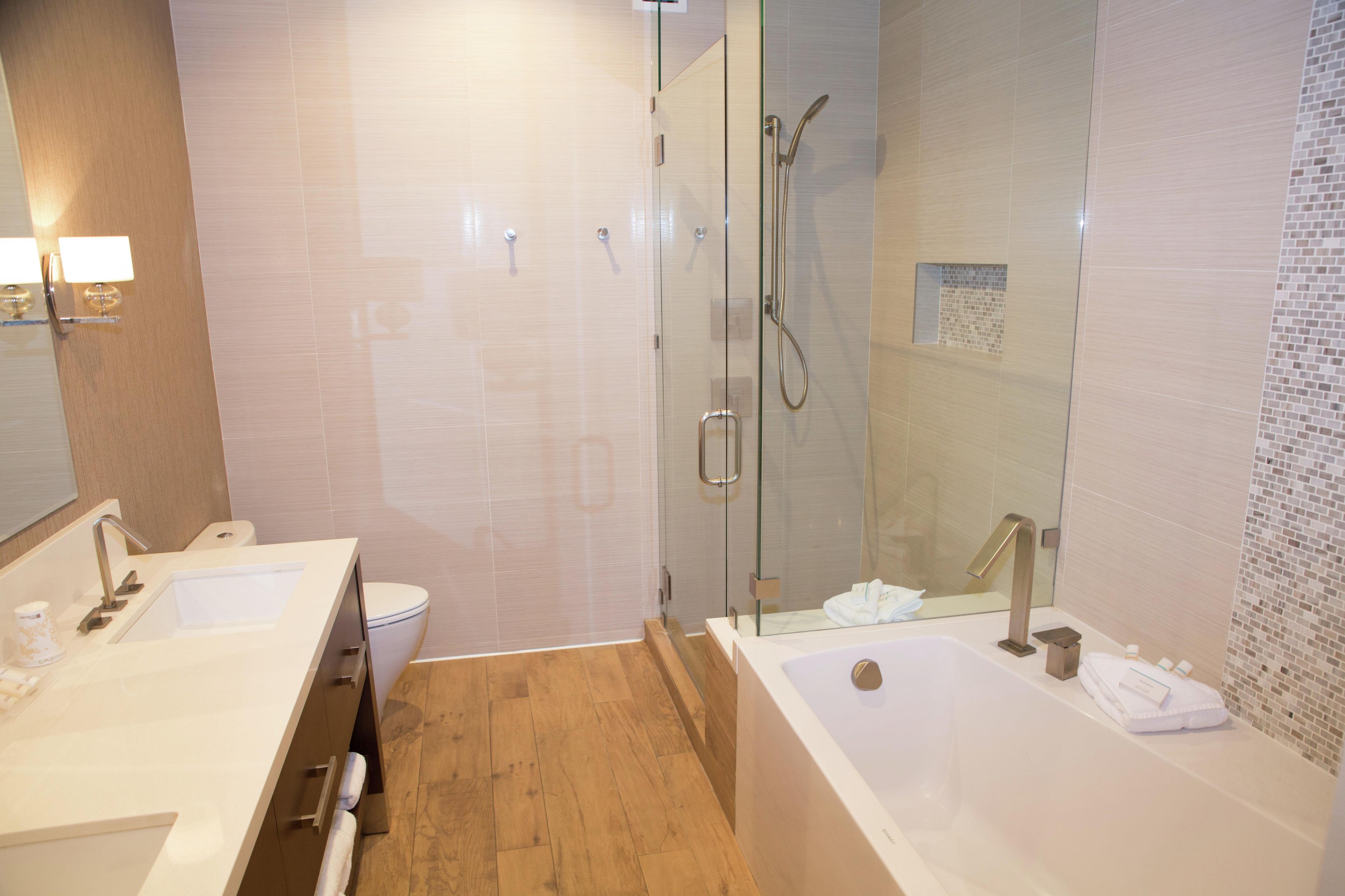 A modern bathroom with a glass-enclosed shower, a double sink vanity, and a large bathtub.