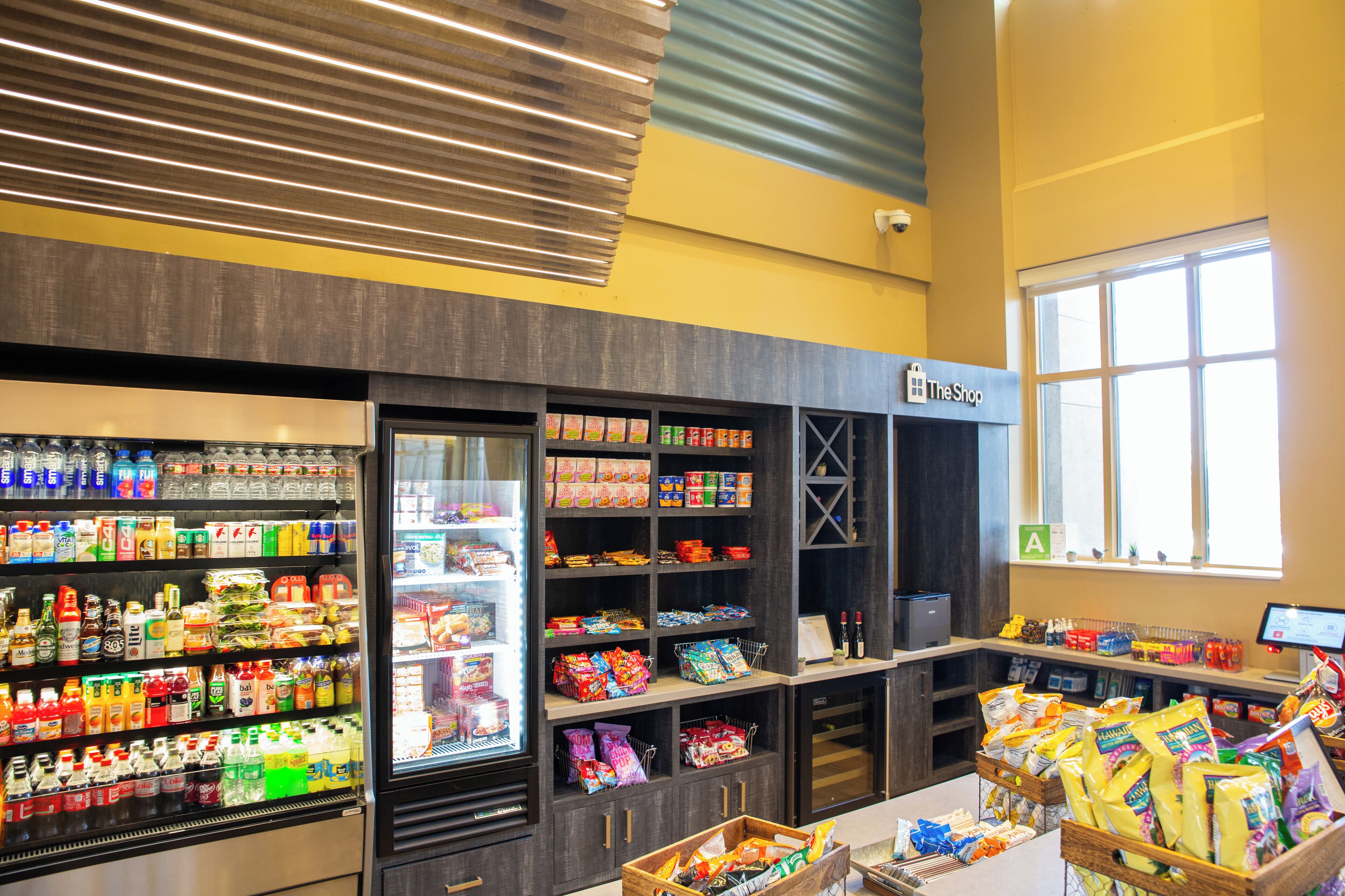 Interior de un supermercado con secciones refrigeradas, estantes llenos de productos y una zona de cajas.