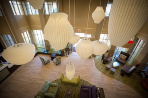 A spacious lobby with multiple seating areas, large hanging pendant lights, and a visible exit sign. - Hilton Garden Inn Los Angeles Montebello (Montebello)