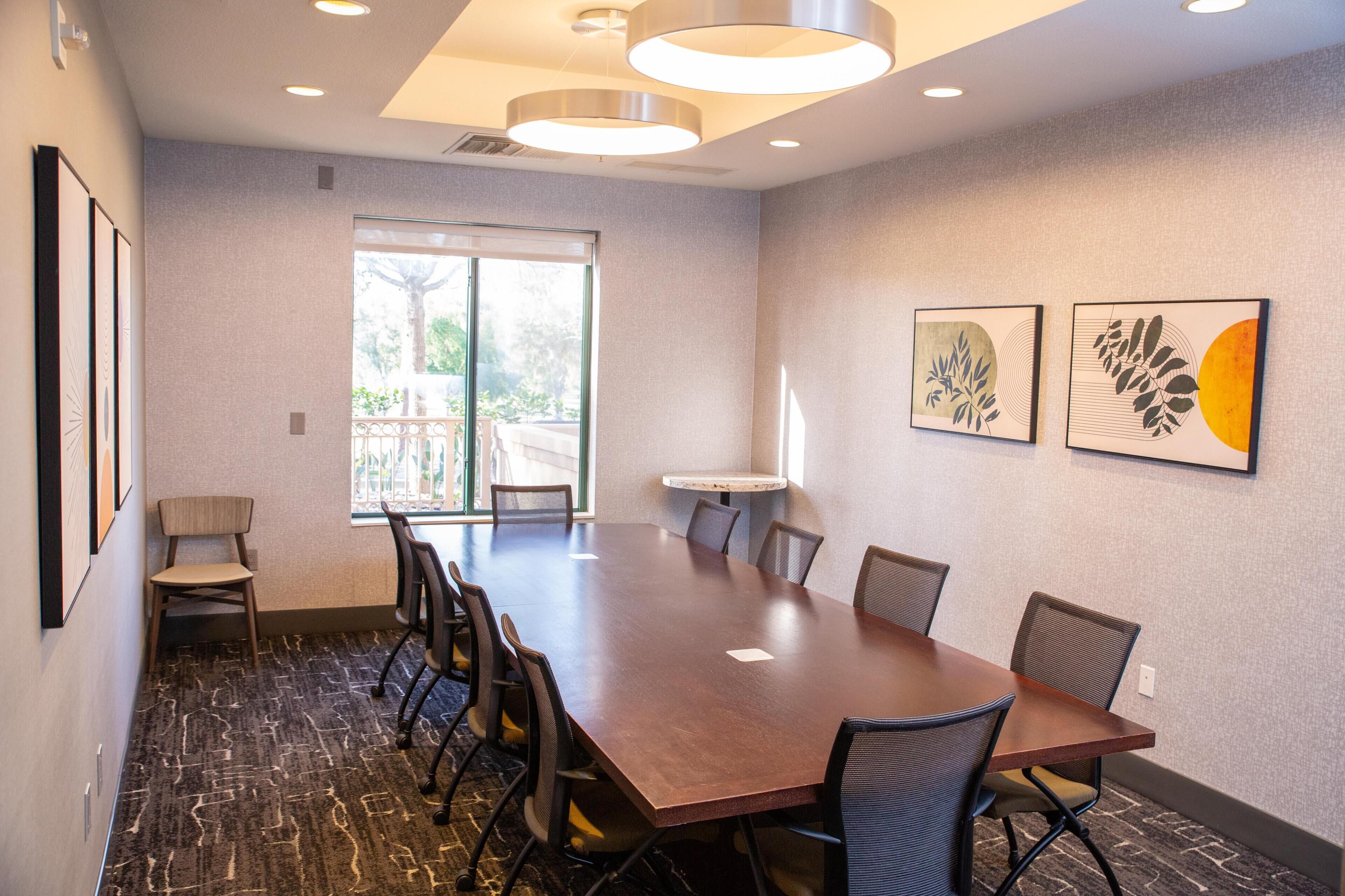 A conference room with a long table, chairs, and artwork on the walls.