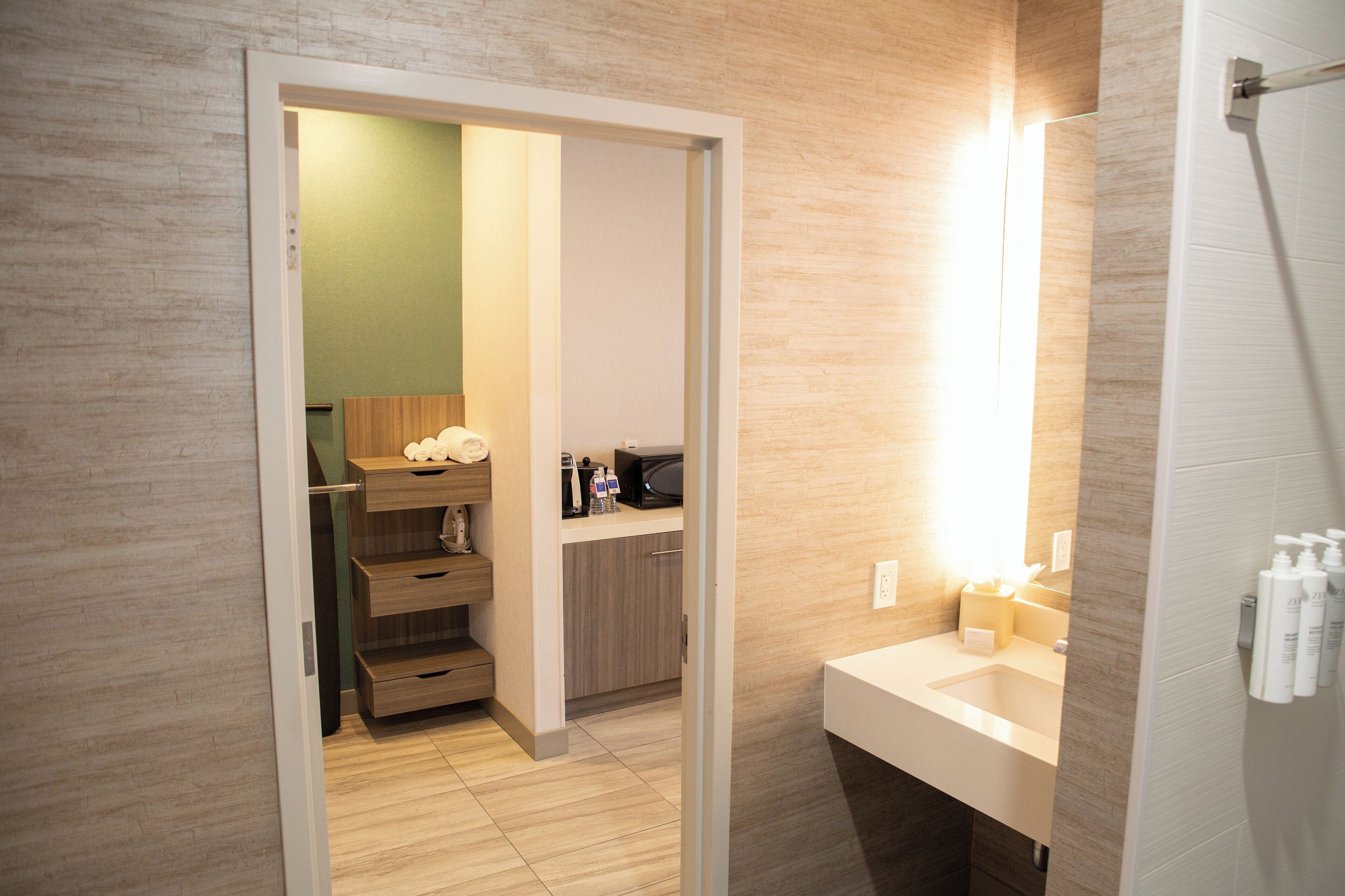A modern bathroom with a wooden vanity, a mirror, and a shower area.