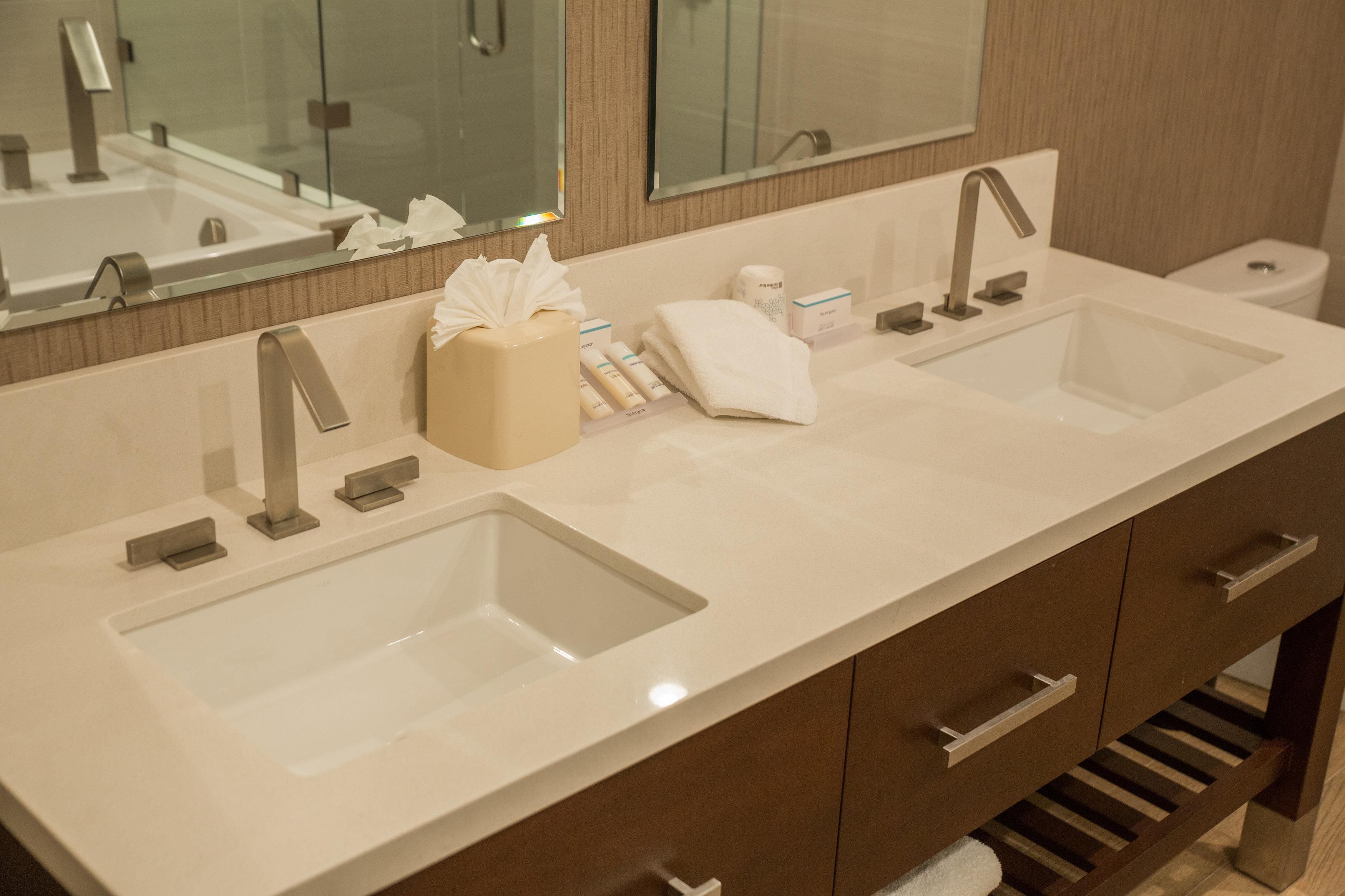 A bathroom with two sinks, a mirror, and a towel dispenser.