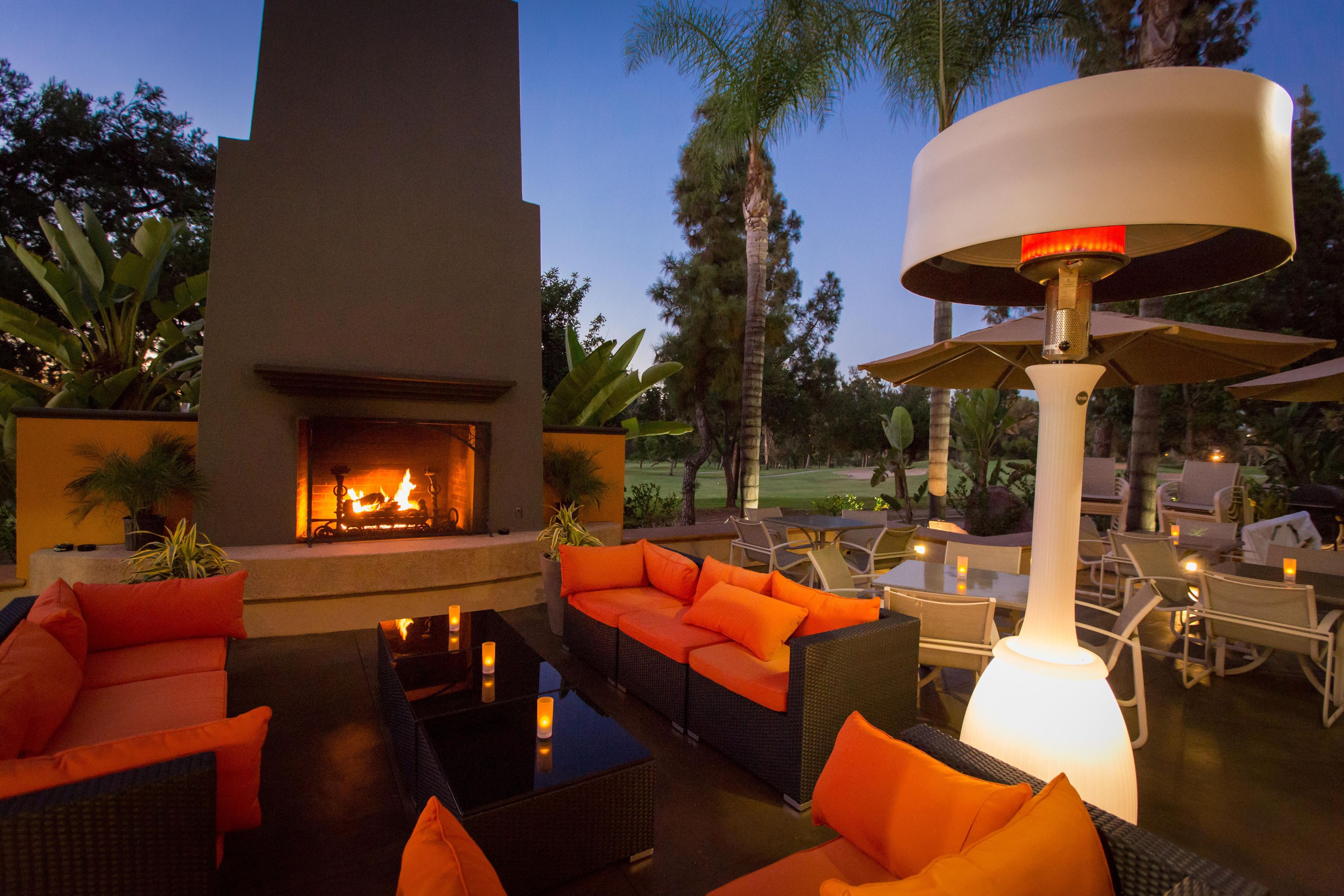 Un área de estar al aire libre con chimenea, sillones y una mesa.
