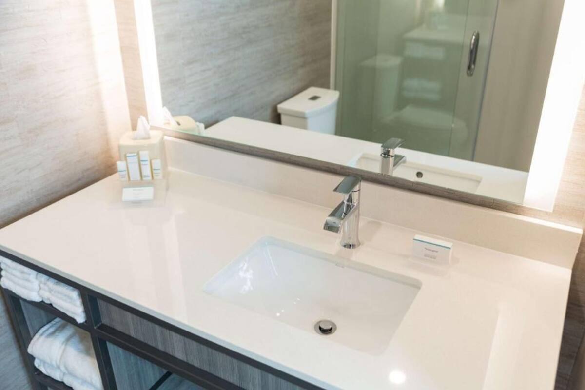 A bathroom with a white sink, a mirror, and a towel rack.
