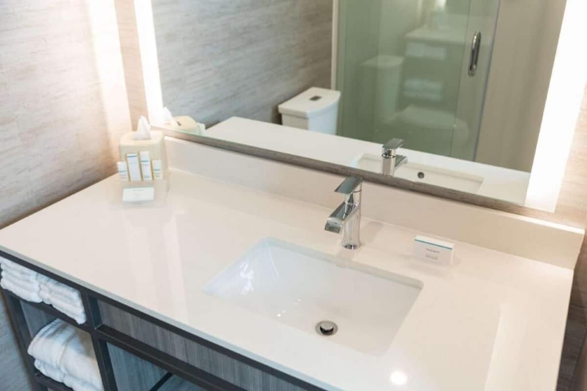 A bathroom with a white sink, a mirror, and a towel rack.