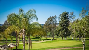 Un campo de golf con árboles, cielo despejado y césped cuidado.