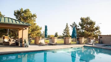 Una piscina al aire libre, sillones reclinables de piscina