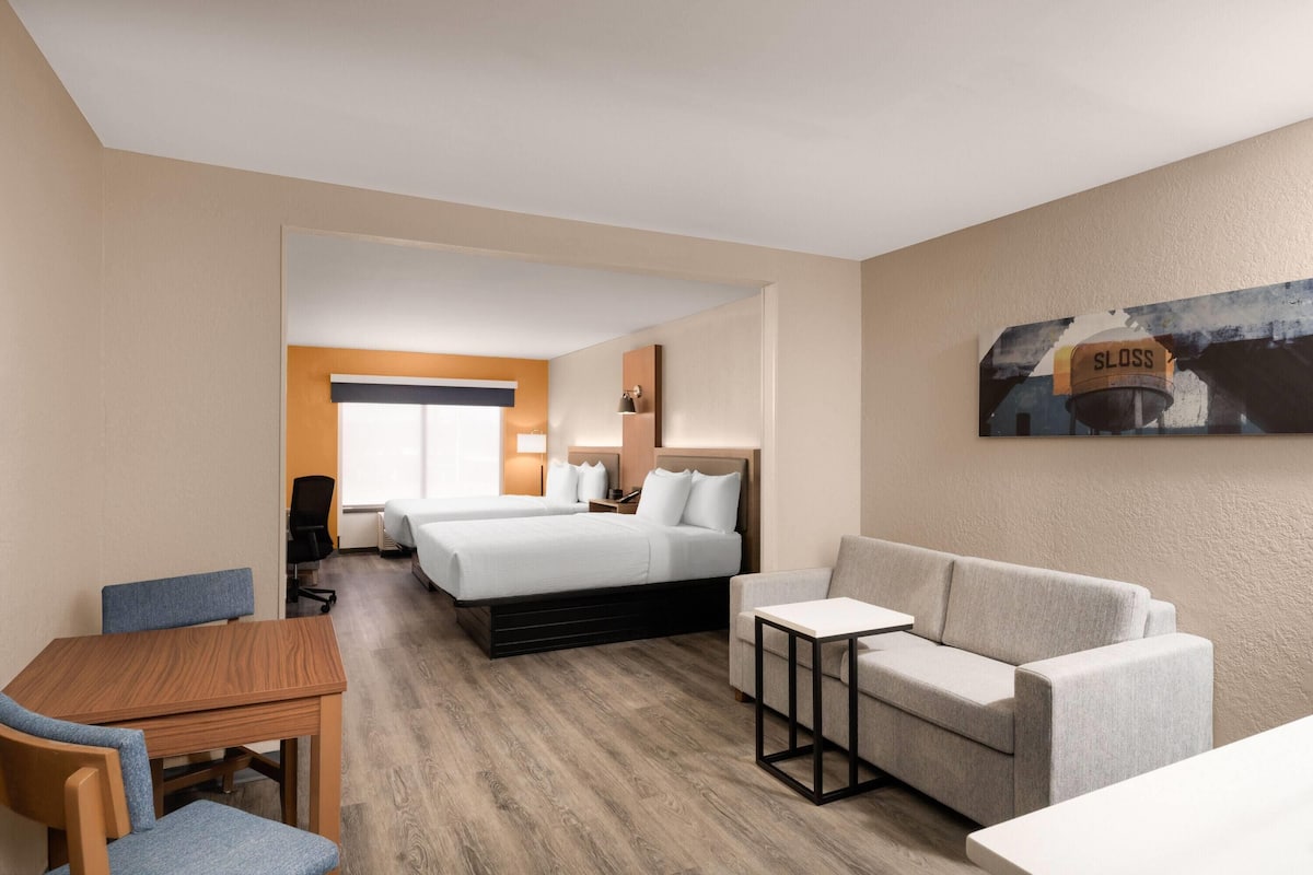 Quarto de hotel com cama, sofá, mesa e cadeira.
