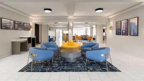 A spacious lobby with a central seating area, a reception desk, and framed artwork on the walls. - La Quinta Inn & Suites by Wyndham Bessemer (Bessemer)
