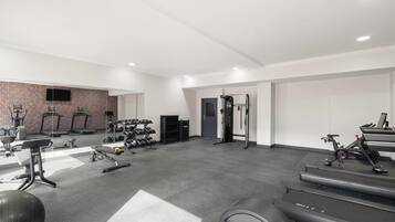 Un gimnasio con cintas de correr, máquinas de pesas y pesas libres.
