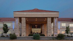 Entrada de hotel con un porche cubierto, columnas de piedra y techo de tejas.