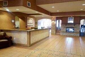 Um lobby amplo com uma mesa de recepção, lareira e uma grande janela.