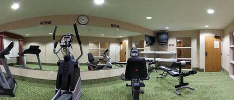 A gym with treadmills, elliptical machines, and weight stations.
