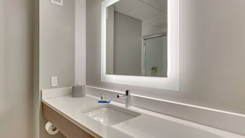 A bathroom with a white sink, a mirror, and a towel rack.
