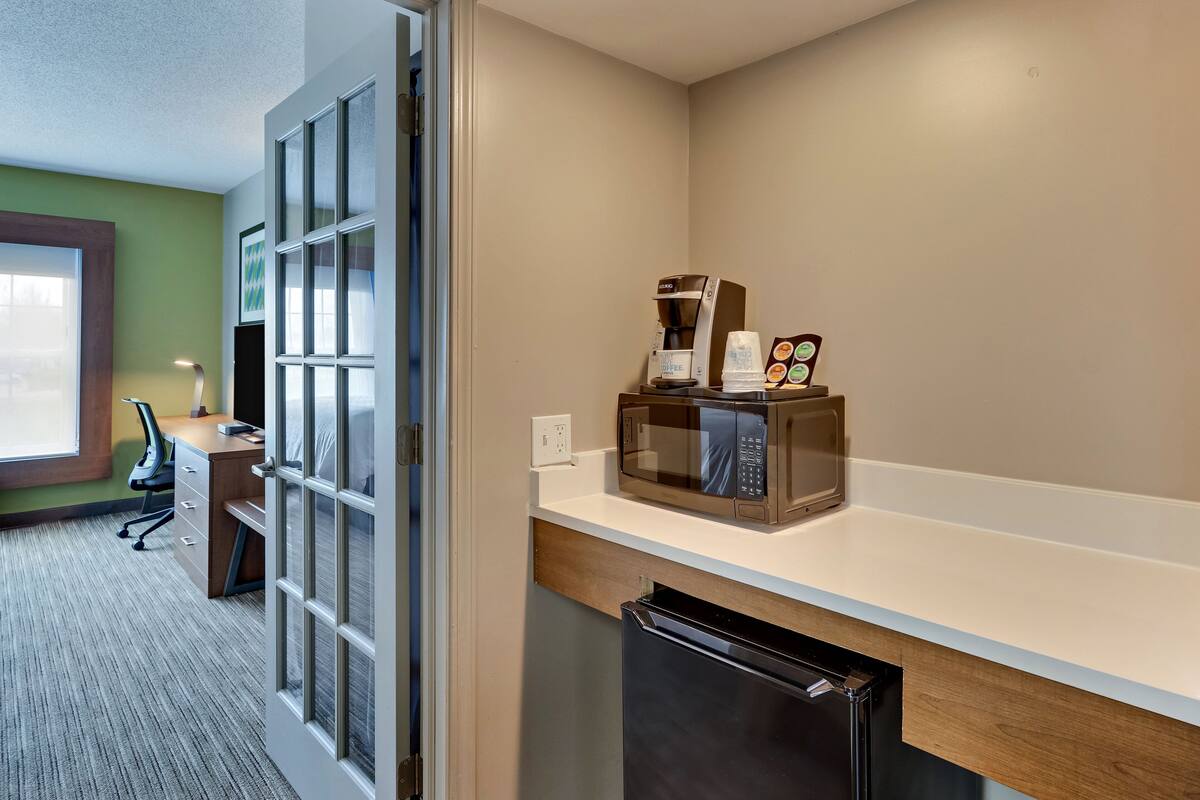 A modern kitchen with a microwave, coffee maker, and a refrigerator.