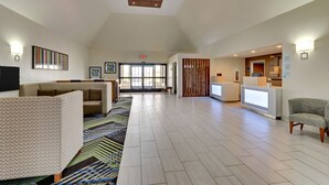A spacious lobby with a high ceiling, a reception desk, seating area, and a large window providing natural light. - Holiday Inn Express Hotel & Suites Bad Axe by IHG (Bad Axe)