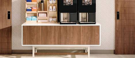 Una zona de cocina con encimera de madera, dos cafeteras y una estantería con utensilios de cocina.