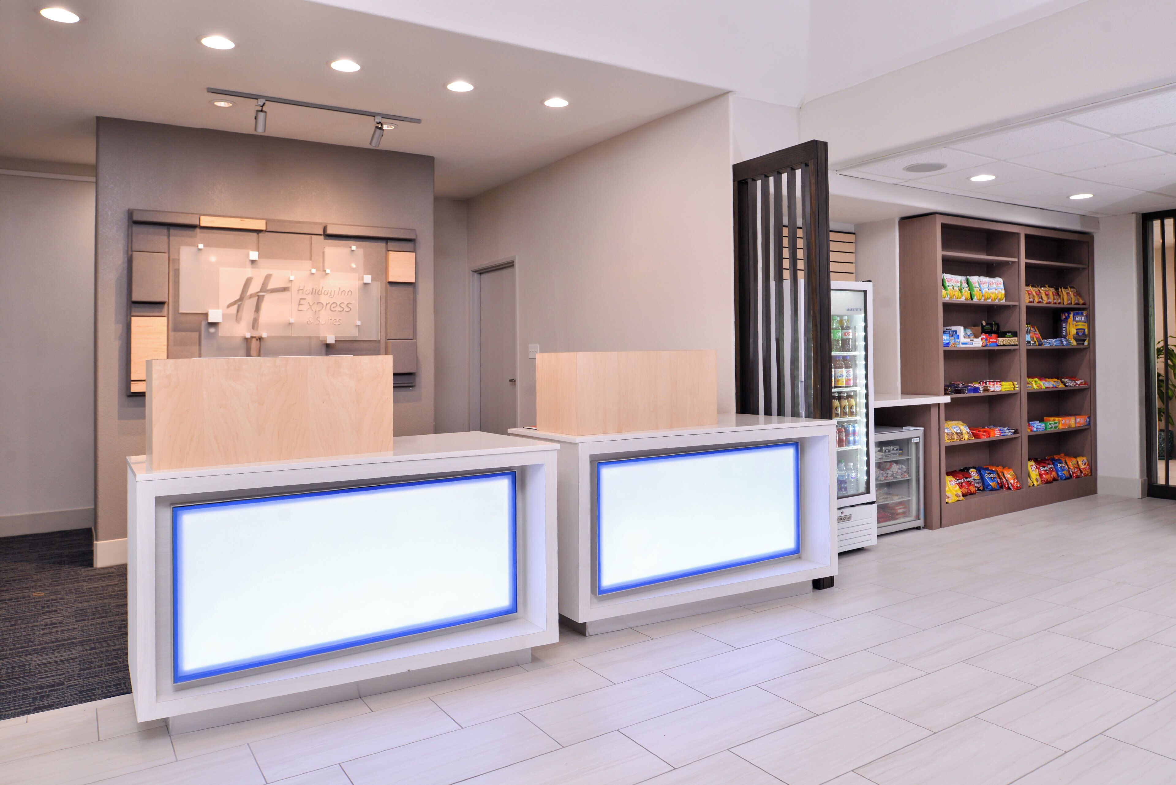 A hotel reception area with a modern design, including a reception desk, a minibar, and a snack bar.