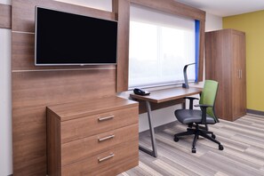 A modern office space with a wooden desk, a chair, a TV mounted on the wall, and a window with blinds. - Holiday Inn Express Hotel & Suites Elgin by IHG (Elgin)