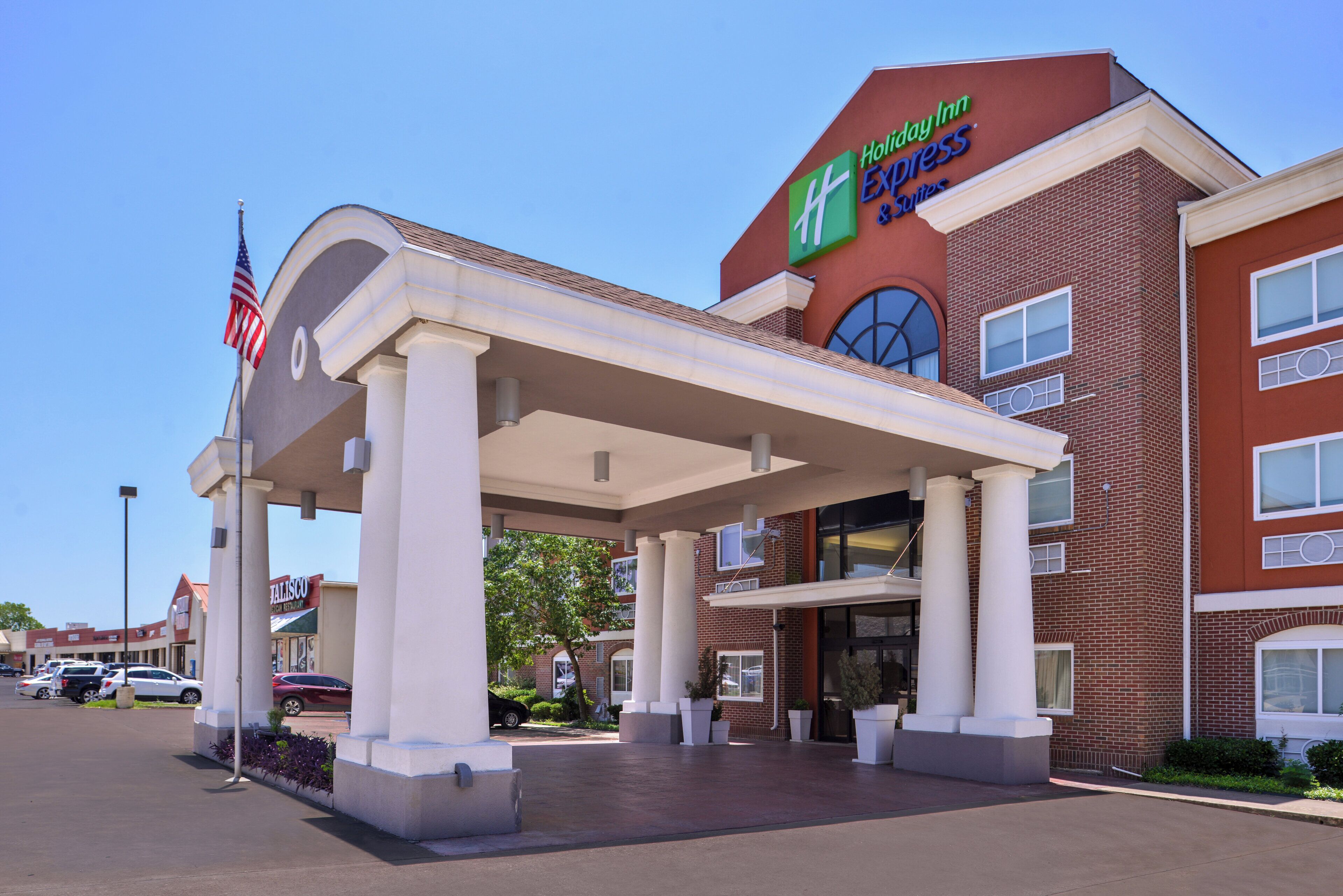 Un hôtel Holiday Inn Express doté d’une entrée couverte, d’un drapeau américain et d’une façade en briques.