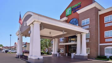 Un hôtel Holiday Inn Express doté d’une entrée couverte, d’un drapeau américain et d’une façade en briques.