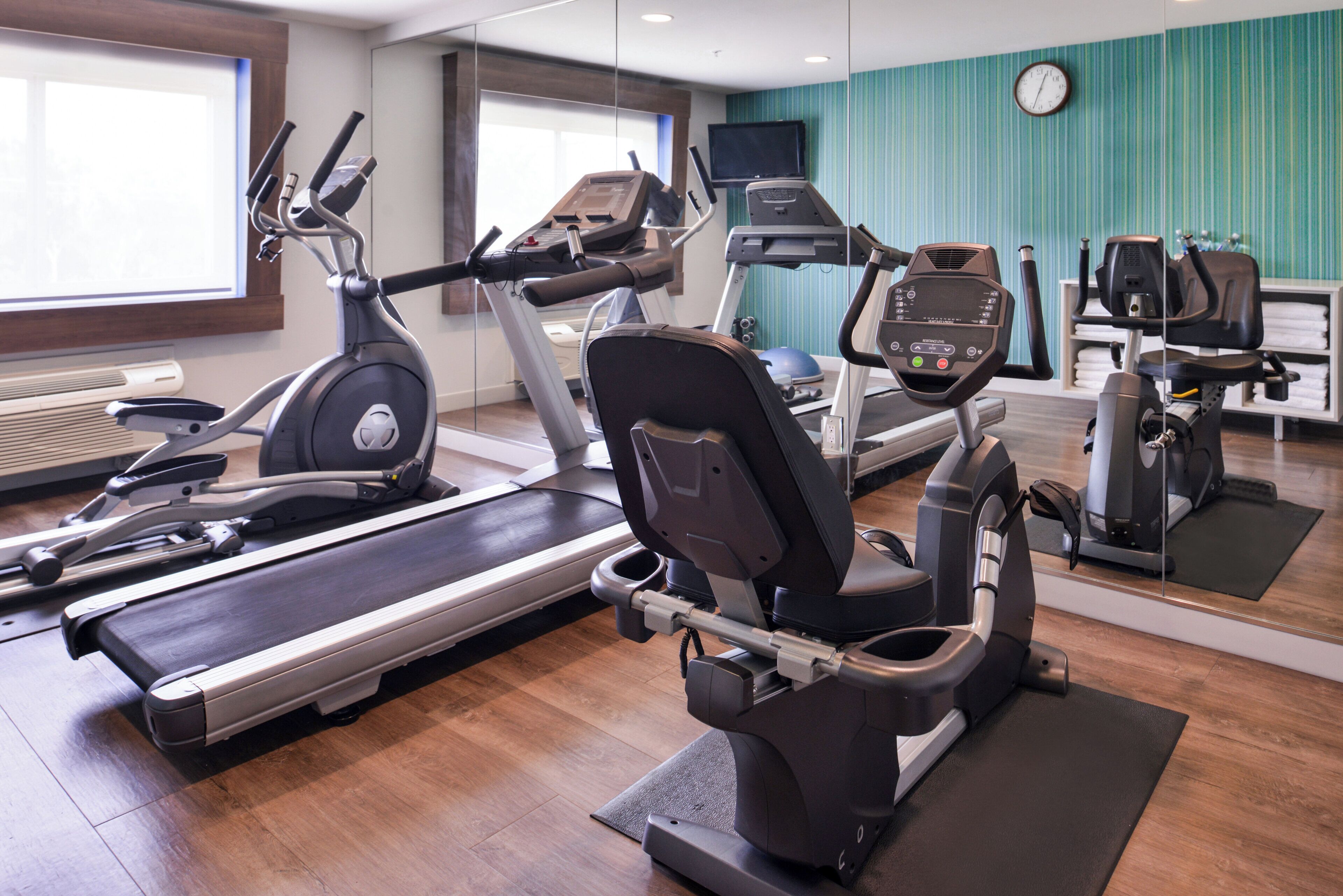 Ein Fitnessstudio mit verschiedenen Trainingsgeräten, darunter Laufbänder, Ergometer und Crosstrainer.