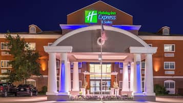 De ingang van een Holiday Inn Express & Suites hotel, met een vlaggenmast, zuilen en een parkeerplaats.