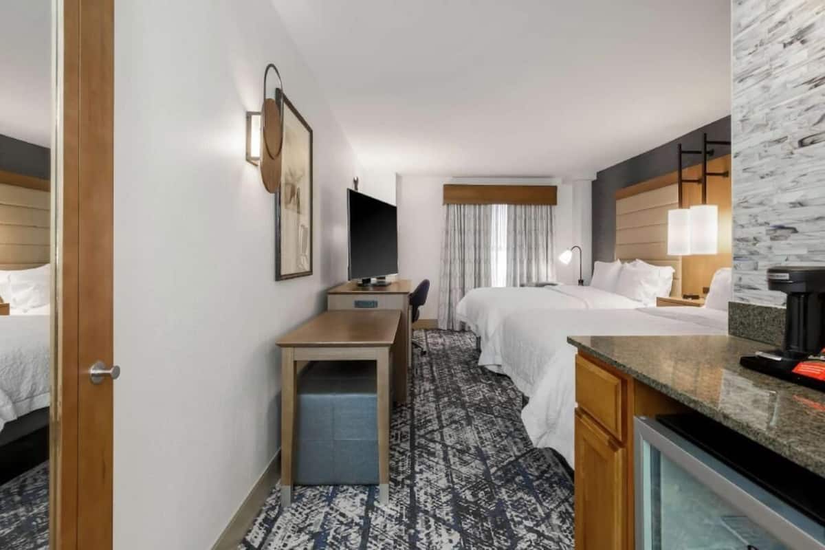 A hotel room with a bed, desk, and a television.