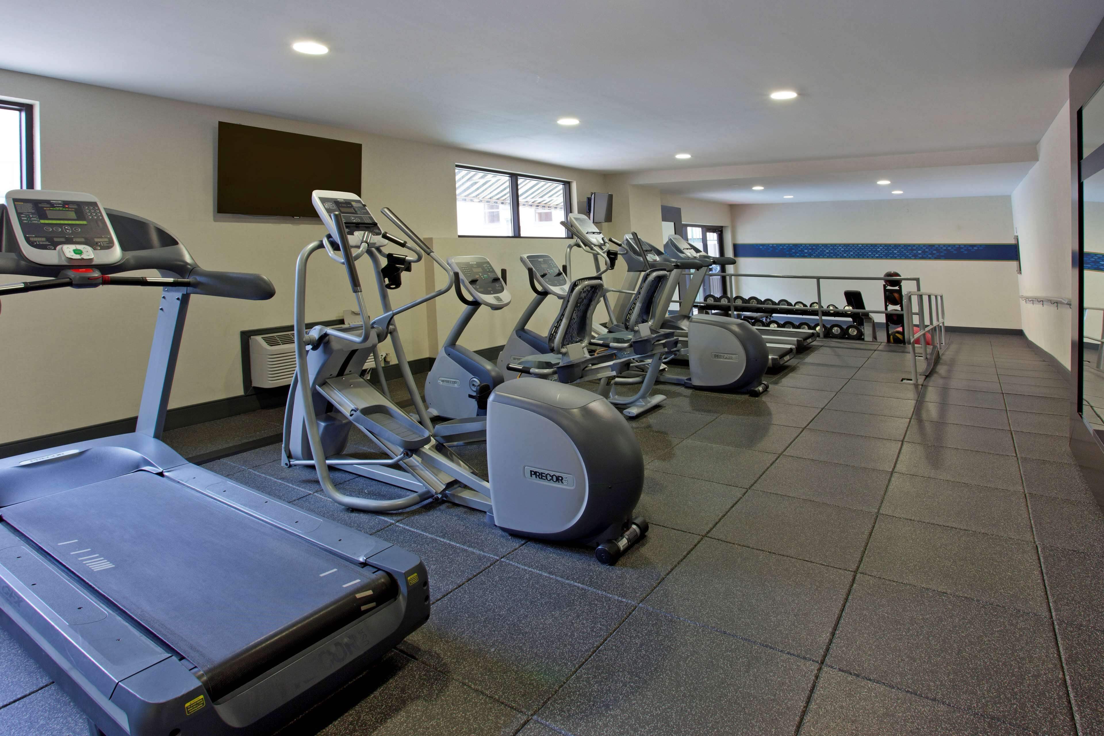 Uma academia com várias esteiras, elípticos e aparelhos de musculação.