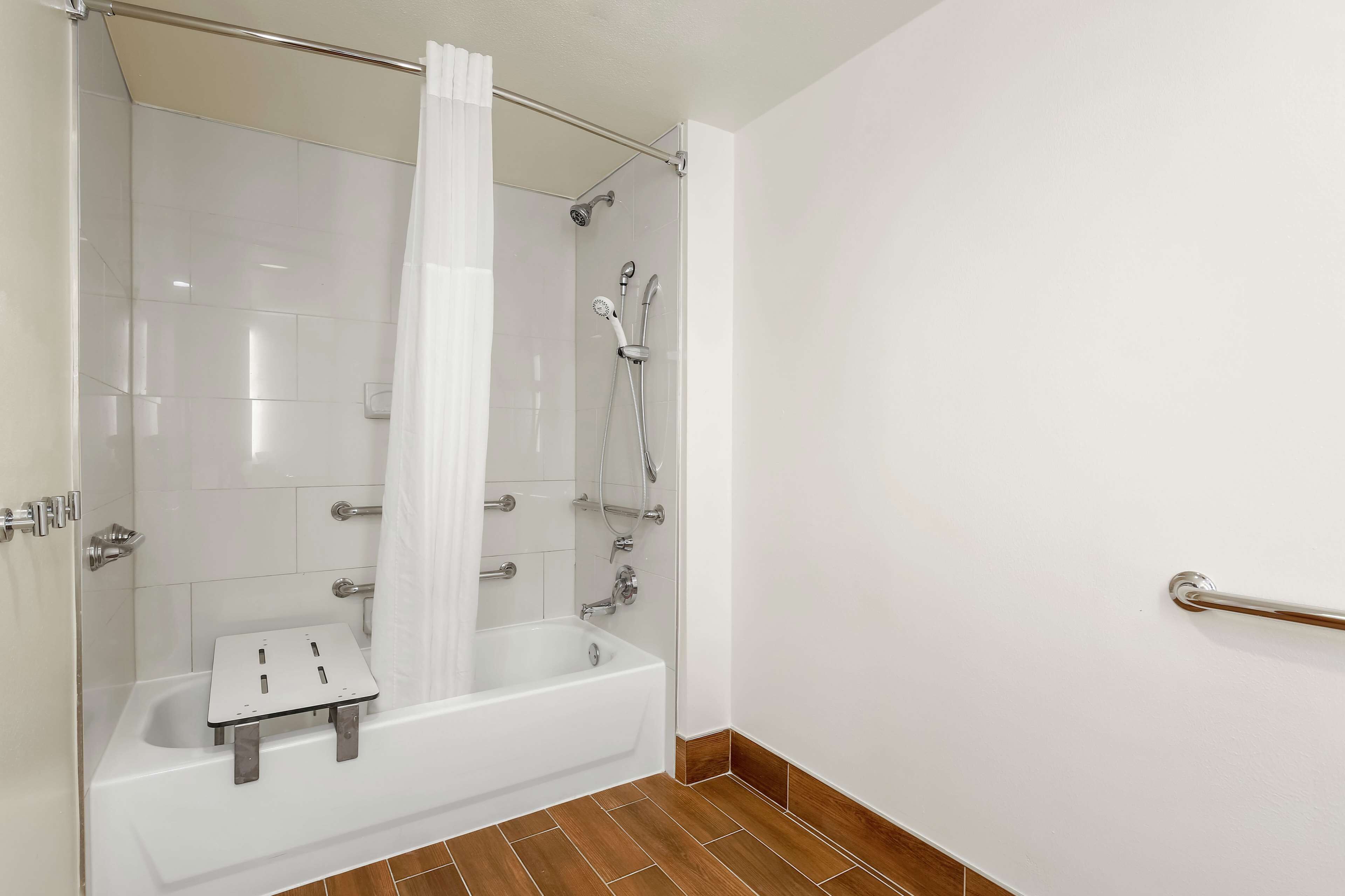 A modern bathroom with a glass-enclosed shower, a white bathtub, and a showerhead.