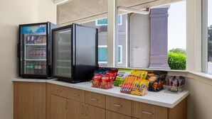 Uma cozinha compacta com geladeira, micro-ondas e janela com vista para edifícios e áreas verdes.