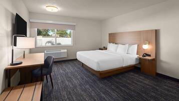 A hotel room with a bed, desk, chair, and a window with a view.
