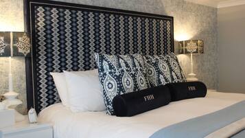 A neatly made bed with patterned pillows and a headboard, a bedside table with a lamp, and a wall with a textured pattern.