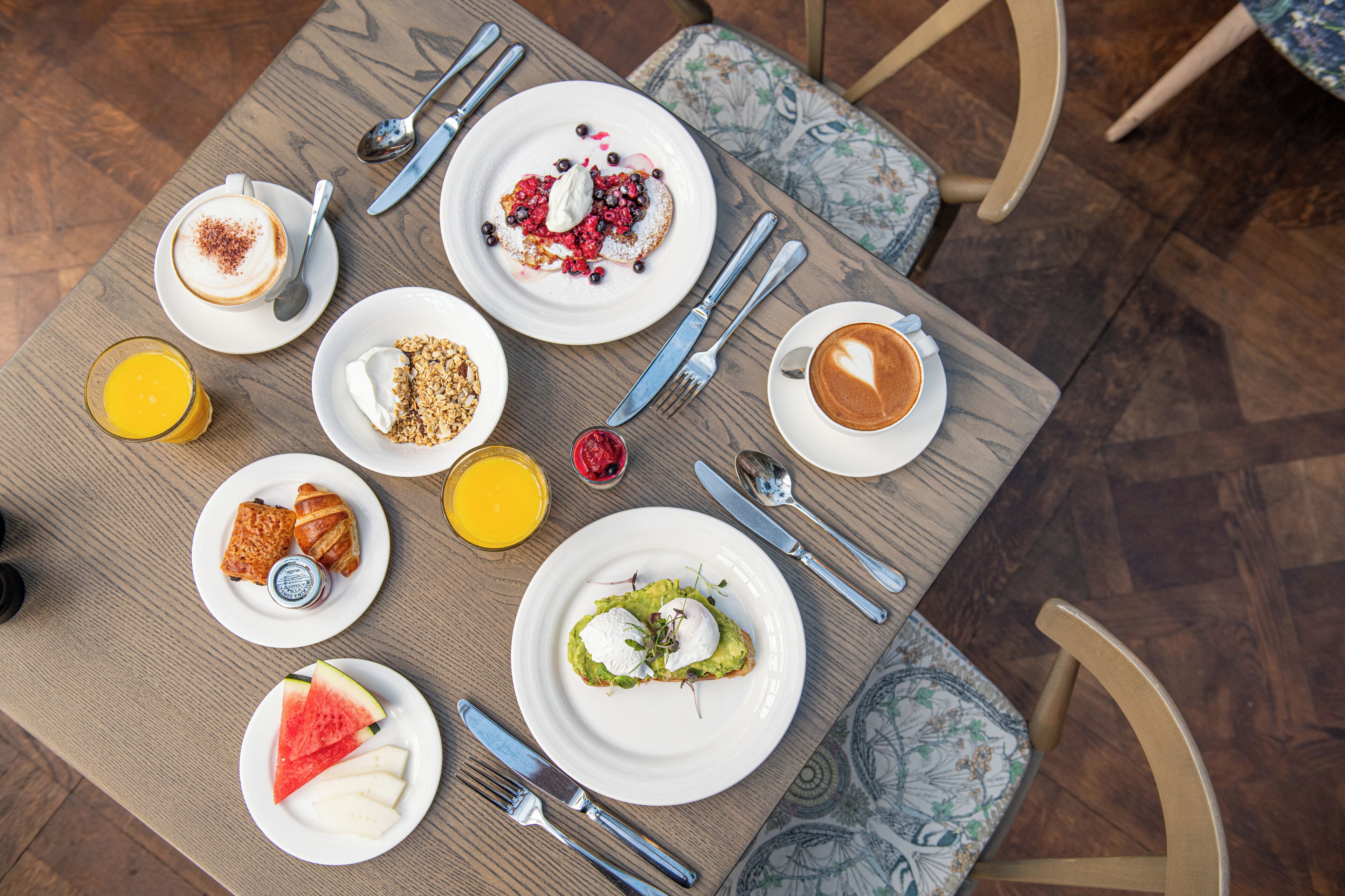 A breakfast table with various dishes, including toast, fruit, yogurt, and coffee.
