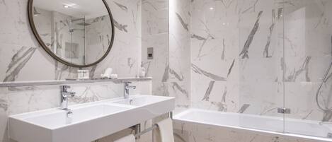 A modern bathroom with two sinks, a bathtub, and a shower.