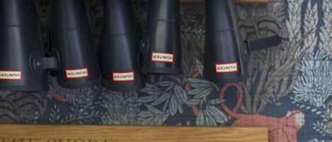 A display of binoculars in black and red colors on a wooden shelf against a patterned wall.