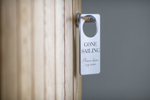 A door with a sign that reads "GONE SAILING Please clean my room."