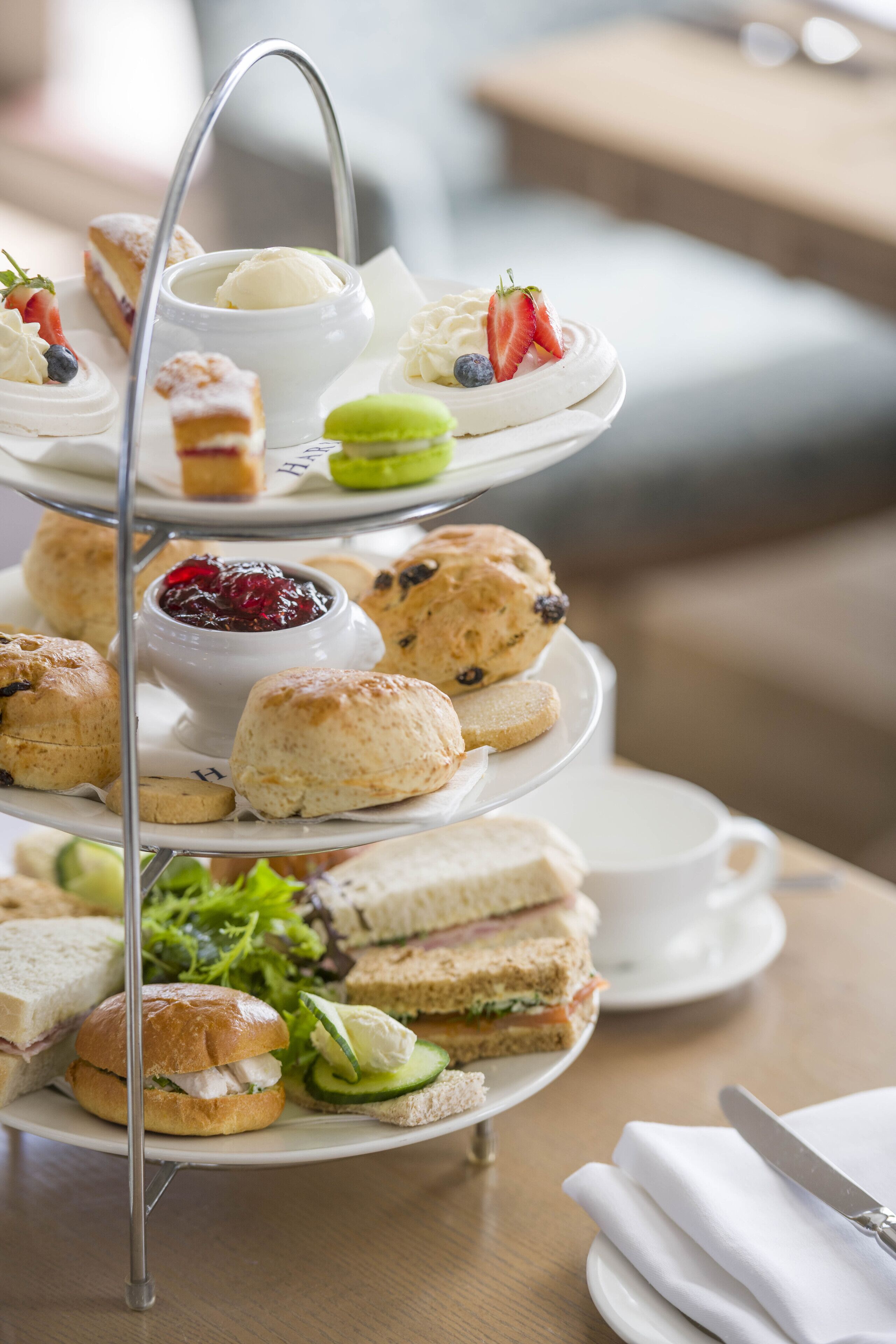 A multi-tiered tray of assorted sandwiches, scones, and desserts.