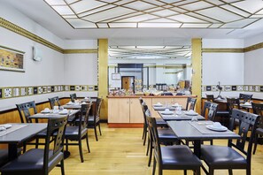A restaurant with wooden tables and chairs, a central counter with food items, and a patterned ceiling. - Hotel Opera d'Antin (Paris)