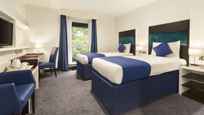 A hotel room with two beds, a desk, a chair, a TV, and a window with curtains. - Ramada by Wyndham Oxford (Oxford)